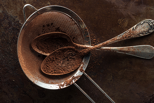 Top view of dirty strainer and vintage spoons on rust metal background