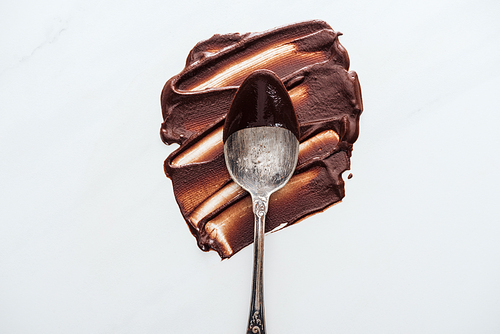 Top view of vintage spoon with melted chocolate on white background