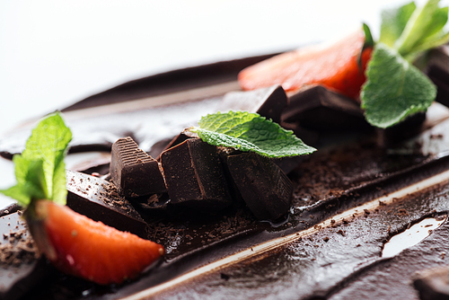 Close up view of pieces of chocolate bar, strawberries and fresh mint