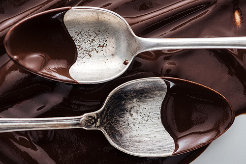 Close up view of spoons covered of chocolate on melted chocolate background