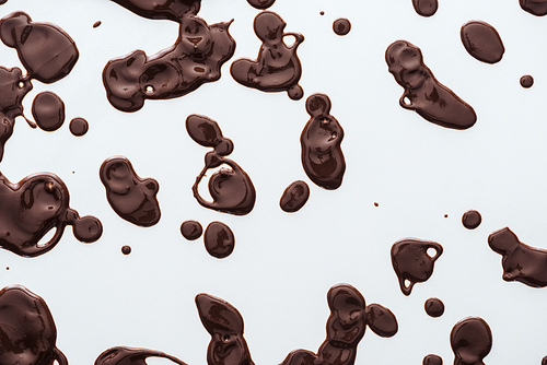 Top view of drops of liquid dark chocolate on white background