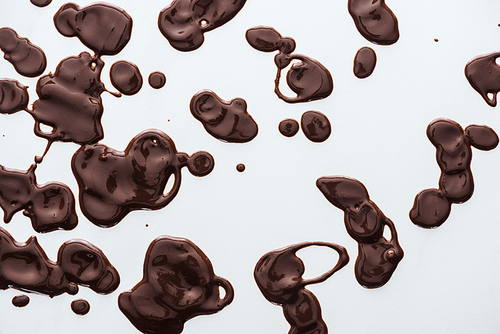 Top view of drops of melted dark chocolate on white background