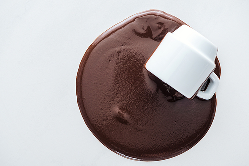 Top view of cup with spilling chocolate on white background