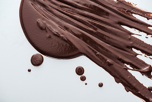 Top view of spilled dark chocolate and chocolate drops on white background