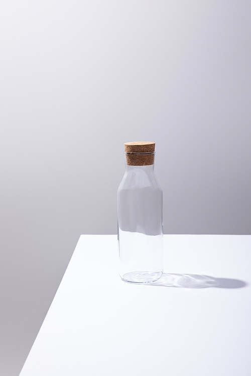 empty glass bottle with cork on white surface isolated on grey
