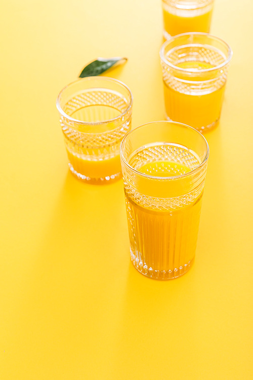 selective focus of glasses of fresh delicious yellow smoothie near green leaf