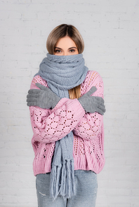 Young woman in knitwear and gloves suffering from cold on white background