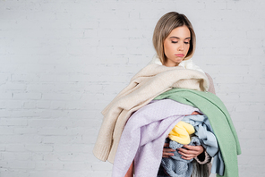Young woman holding knitted sweaters on white background