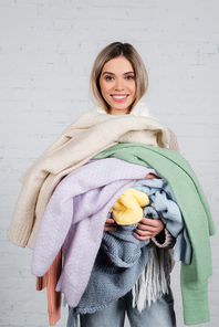 Smiling woman holding knitted sweaters and  on white background