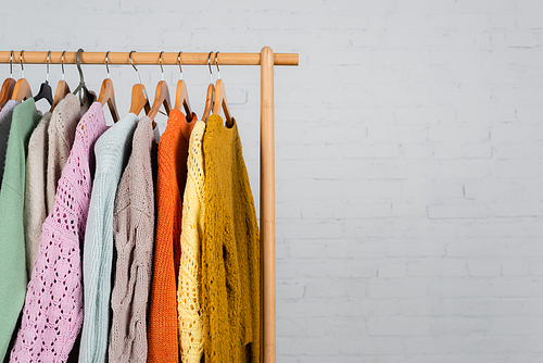 Wooden hanger rack with warm sweaters on white background