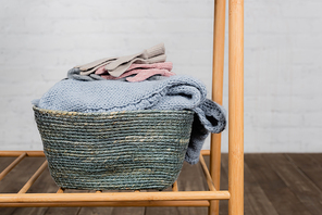 Gloves and warm knitted sweater in basket on hanger rack