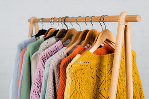 Hangers with colorful sweaters on hanger rack on white background