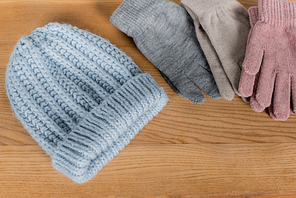 Top view of knitted hat and gloves on wooden surface