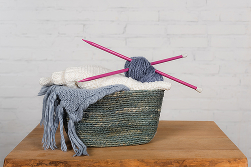 Basket with yarn, needless and thread on wooden table on white background