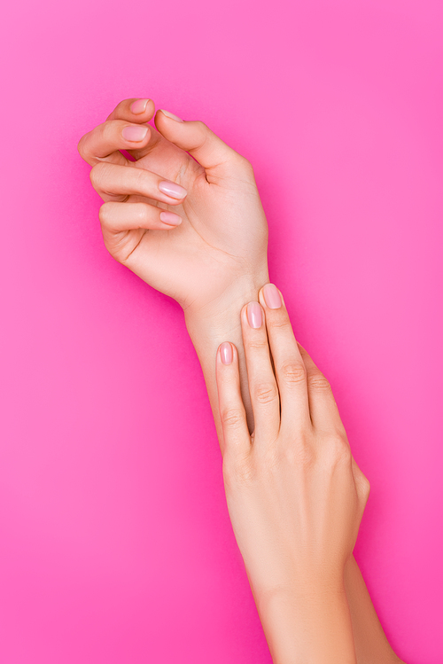 top view of groomed female hands with pastel manicure on pink background