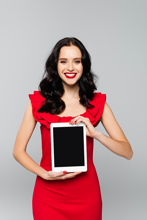 pleased woman with red lips holding digital tablet with blank screen isolated on grey