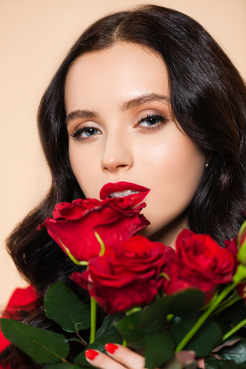 brunette young woman with red lips holding roses isolated on pink