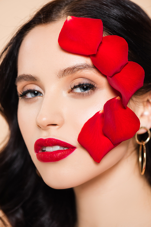 close up of young woman with petals of red rose on face isolated on pink