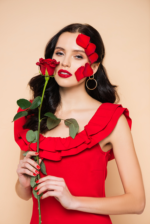 pretty young woman with red lips and petals of rose on face isolated on pink