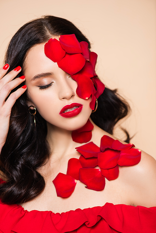 pretty young woman with closed eyes and petals of red rose on face isolated on pink