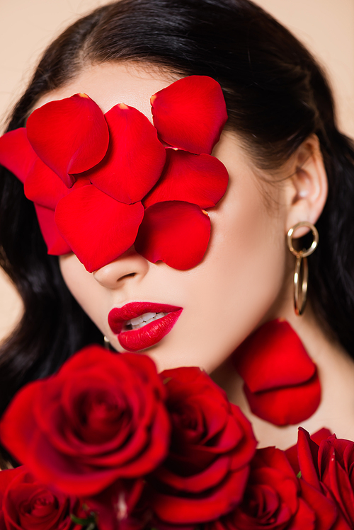 young brunette woman with petals on face and red roses