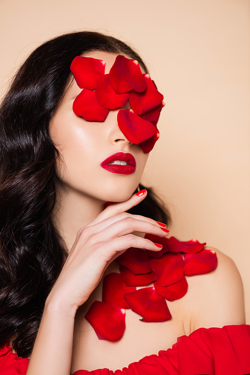 brunette young woman with red rose petals on face isolated on pink