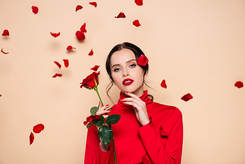 sensual woman with red lips holding red rose near petals and  on pink
