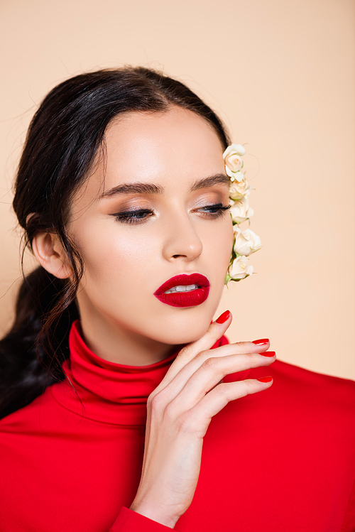 sensual woman with red lips and white flowers on face looking away isolated on pink