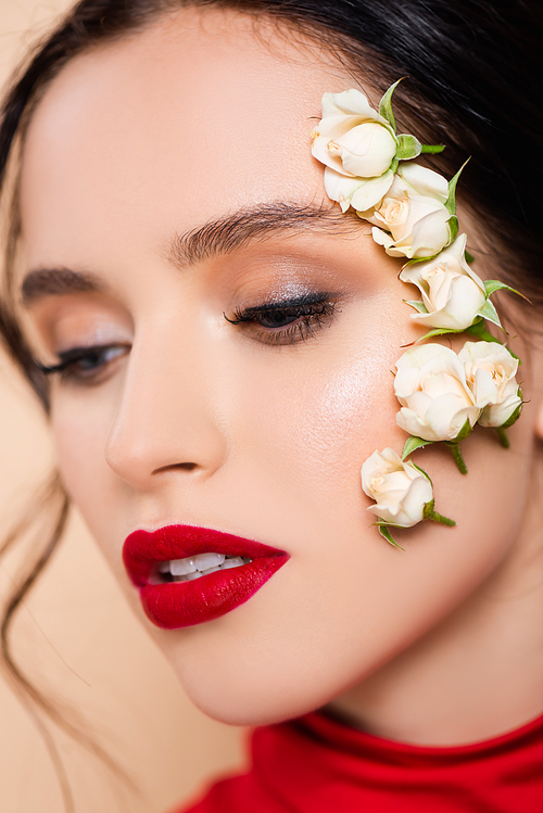 close up of young woman with red lips and flowers on face isolated on pink