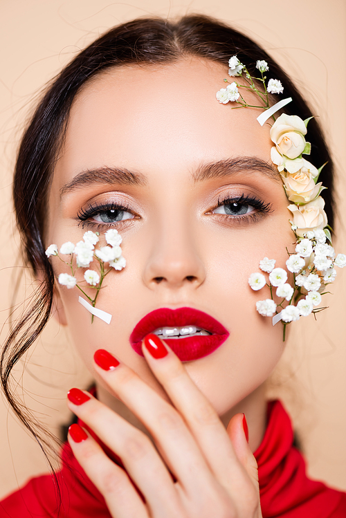 young woman with red lips and white flowers on face  isolated on pink