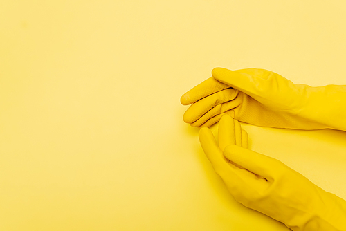 Top view of hands in rubber gloves on yellow background