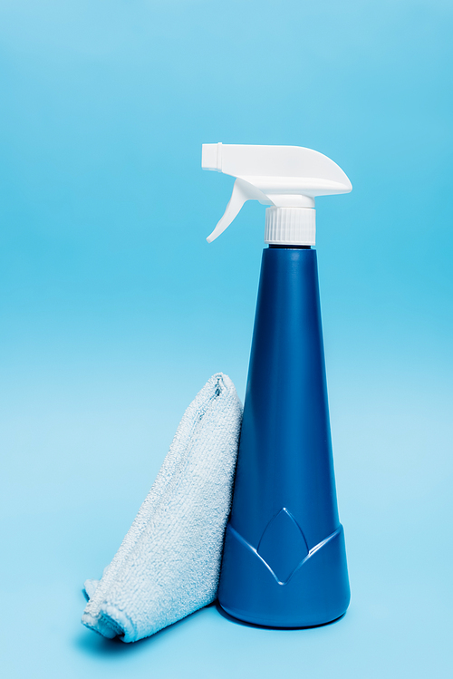 Rag and bottle of detergent on blue background
