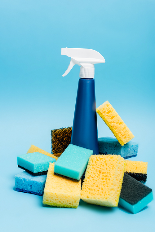 Bottle of detergent and sponges on blurred foreground on blue background
