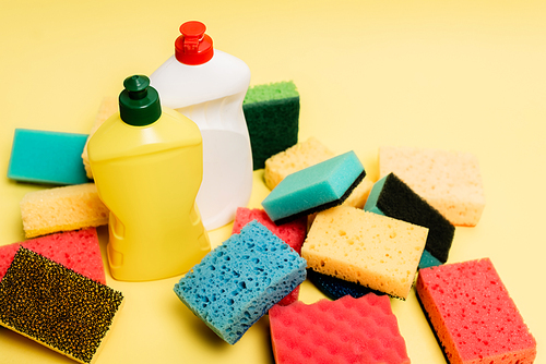 High angle view of dishwashing liquid and sponges on yellow background