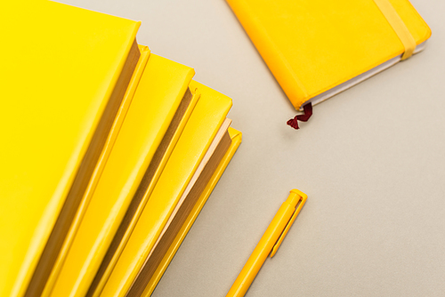 top view of yellow notebooks near pen isolated on grey