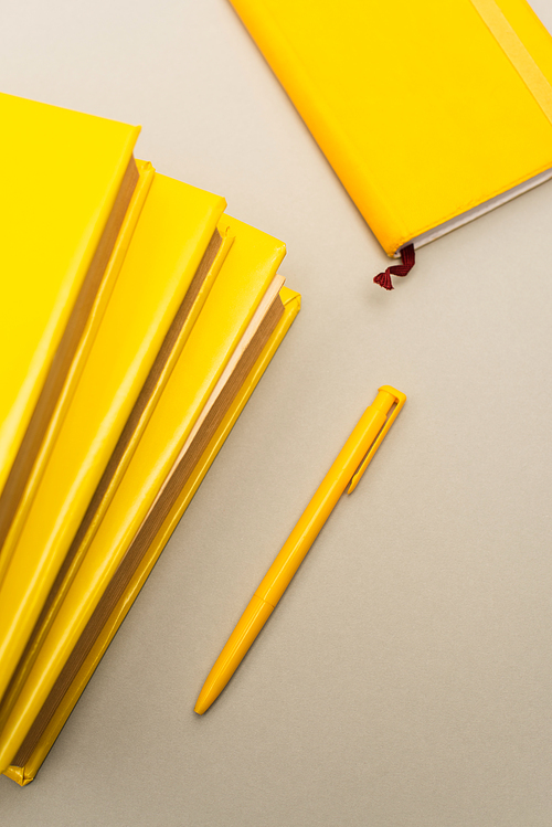 top view of yellow notebooks and pen isolated on grey
