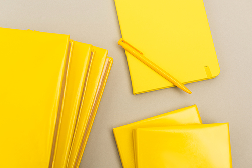 top view of yellow notepads near pen isolated on grey
