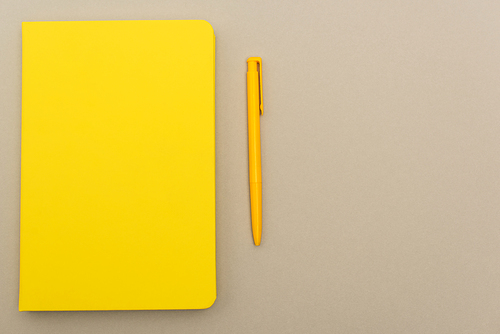 top view of yellow notebook near pen isolated on grey