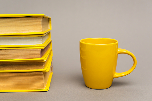 stack of yellow notebooks near mug on grey