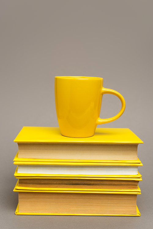 mug on stack of yellow notebooks isolated on grey