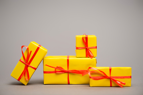 wrapped yellow presents with red ribbons on grey