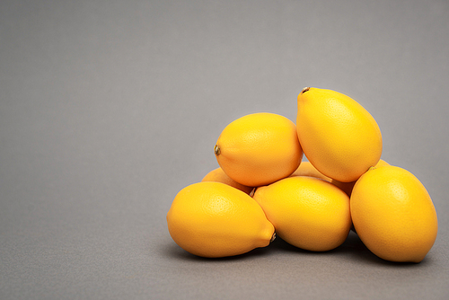 ripe and yellow lemons on grey background