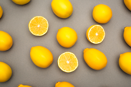 high angle view of halves and whole yellow lemons on grey background