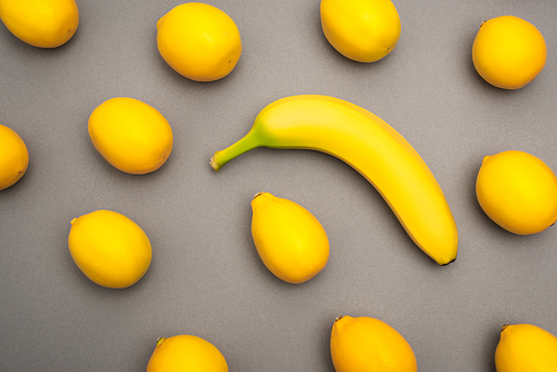 top view of ripe yellow banana and lemons on grey background