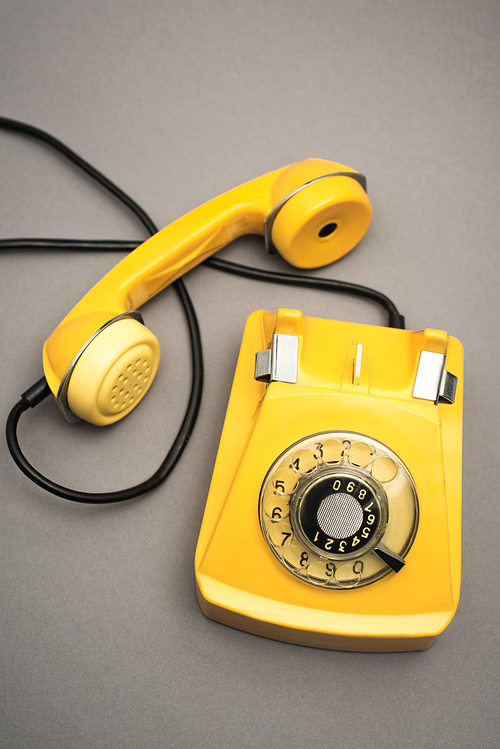 top view of retro and yellow telephone on grey background