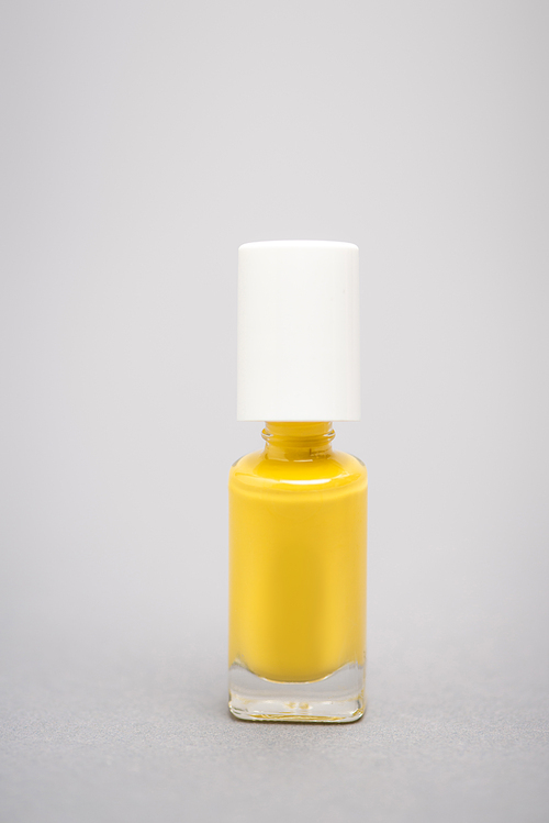 bottle with yellow nail polish on grey background
