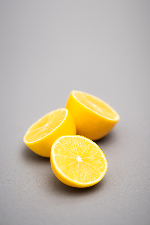 three halves of juicy lemons on grey background