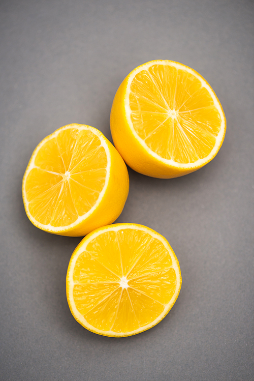 top view of three halves of juicy lemons on grey background