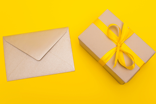 top view of envelope near wrapped present isolated on yellow