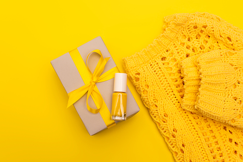 top view of nail polish on wrapped present near jumper isolated on yellow